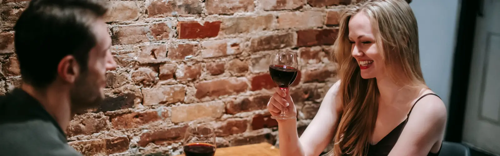 Paar stößt mit Rotwein in gemütlicher Restaurantatmosphäre an.