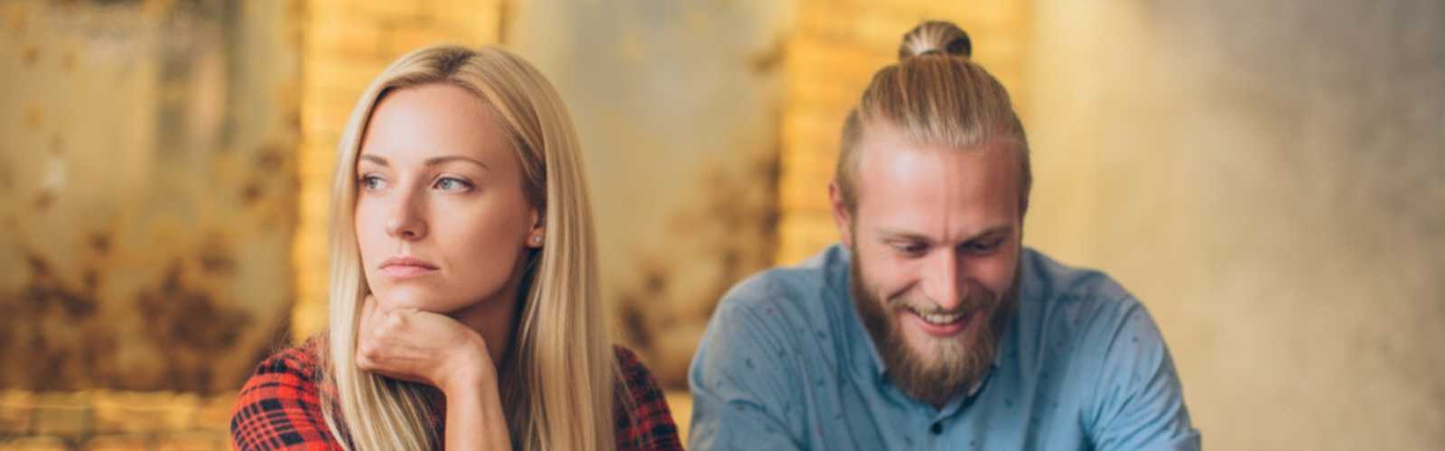 Frau wirkt enttäuscht, während ihr Partner lacht und sie ignoriert.