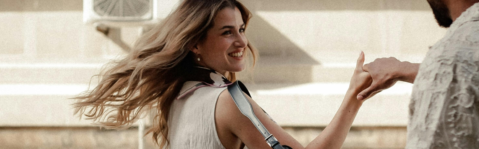 Lächelnde Frau hält die Hand eines Mannes auf der Straße und blickt zurück.