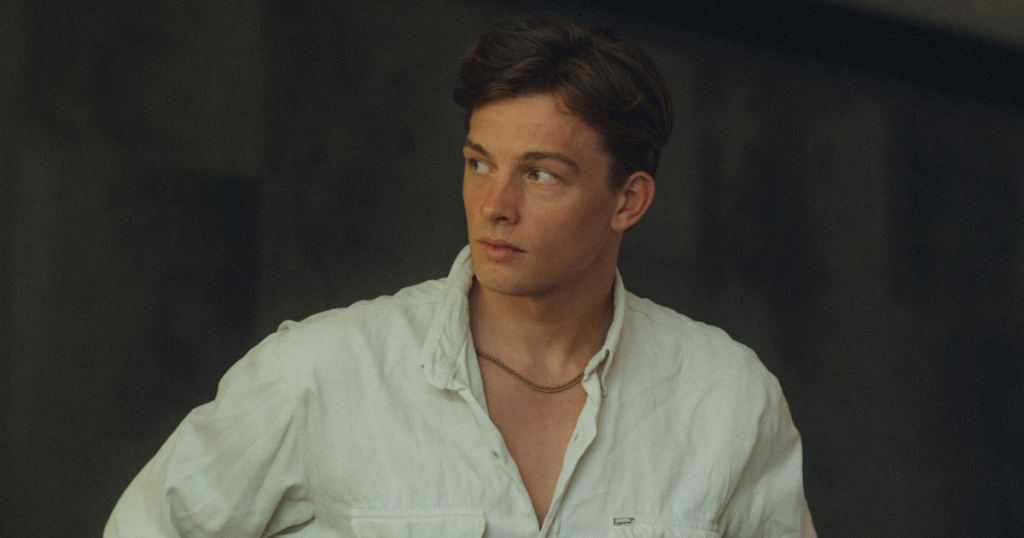 junger Mann im weißen Hemd, der seitlich blickt; Porträt von Brust aufwärts gerahmt.