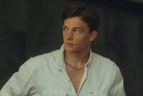 junger Mann im weißen Hemd, der seitlich blickt; Porträt von Brust aufwärts gerahmt.