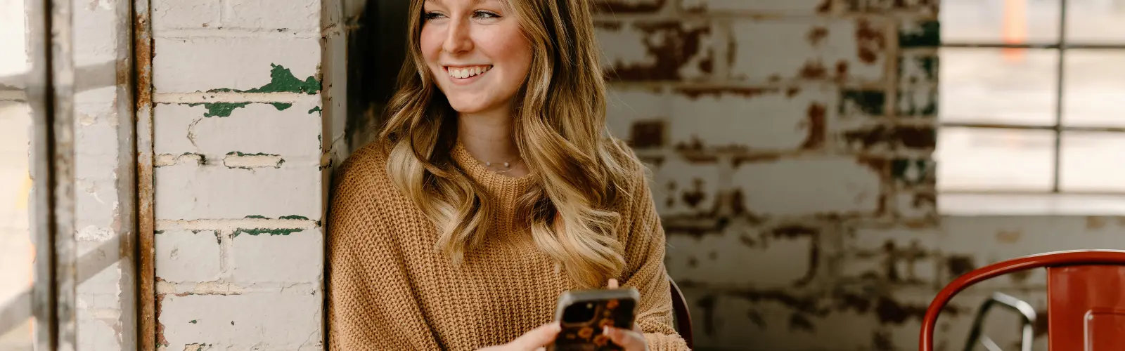 Glückliche Frau mit Smartphone in rostiger Umgebung.