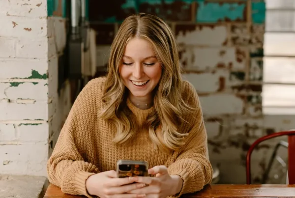 Junge Frau liest lachend eine Textnachricht.