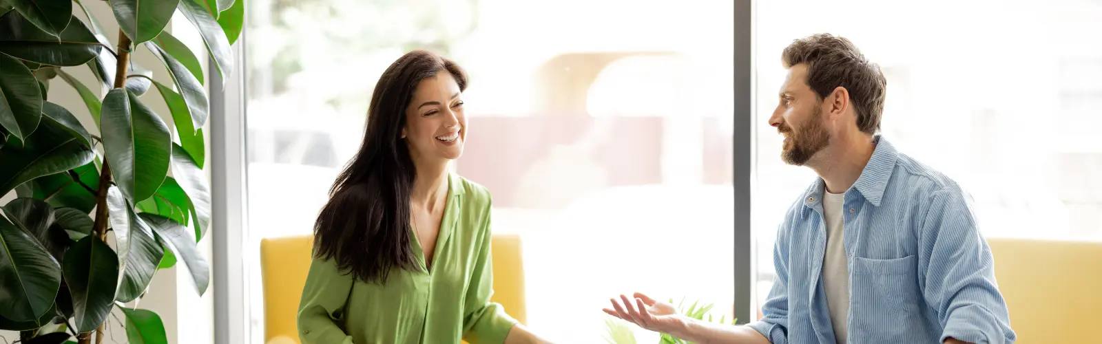 Paar unterhält sich lachend in einem sonnigen Café.