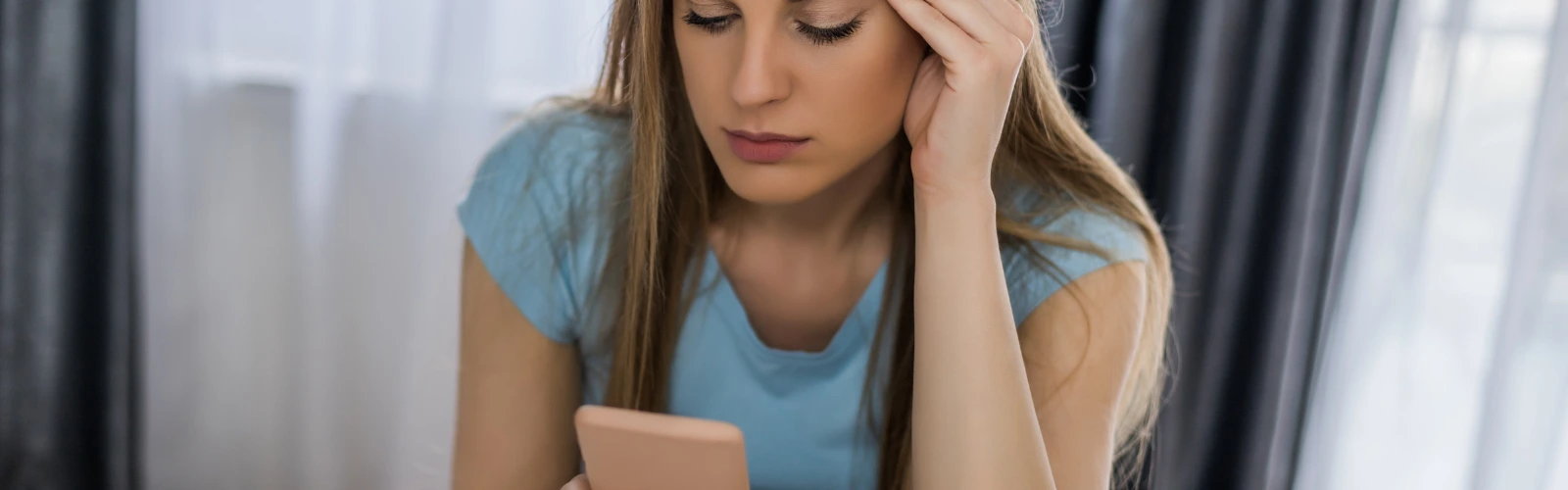 Frau sieht genervt oder verwirrt auf ihr Smartphone.