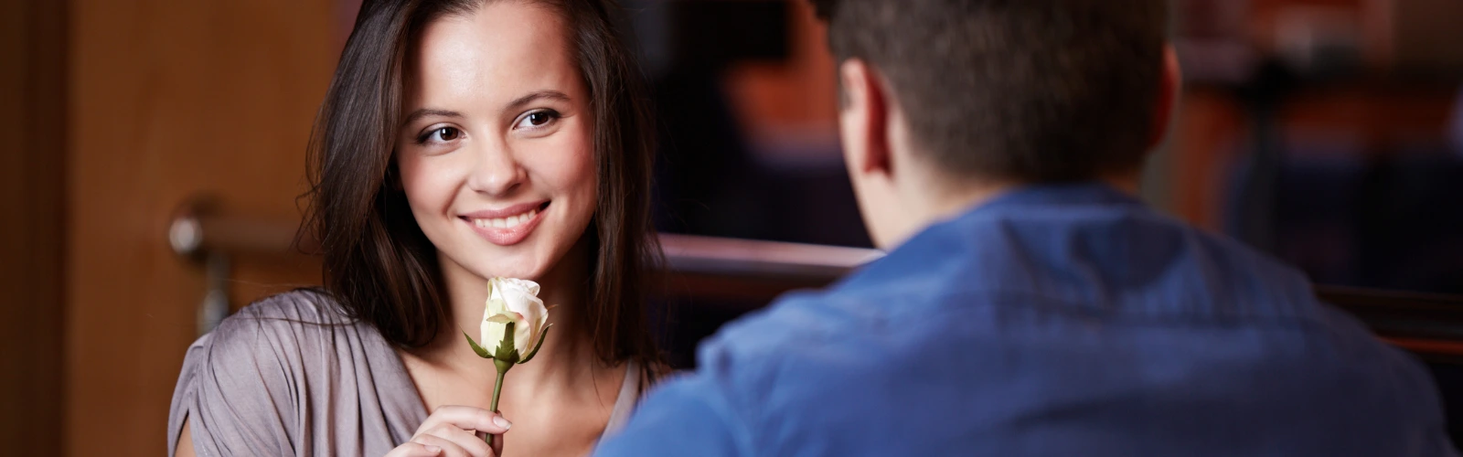 Lächelnde Frau hält eine weiße Rose an einem Date.