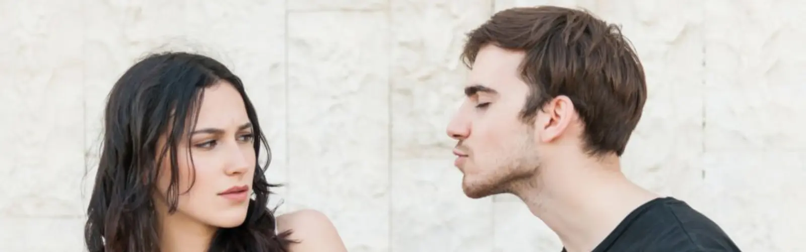 Frau weicht einem Kussversuch des Mannes skeptisch aus.