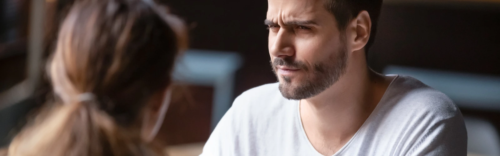 Mann schaut skeptisch und leicht genervt auf sein Date.