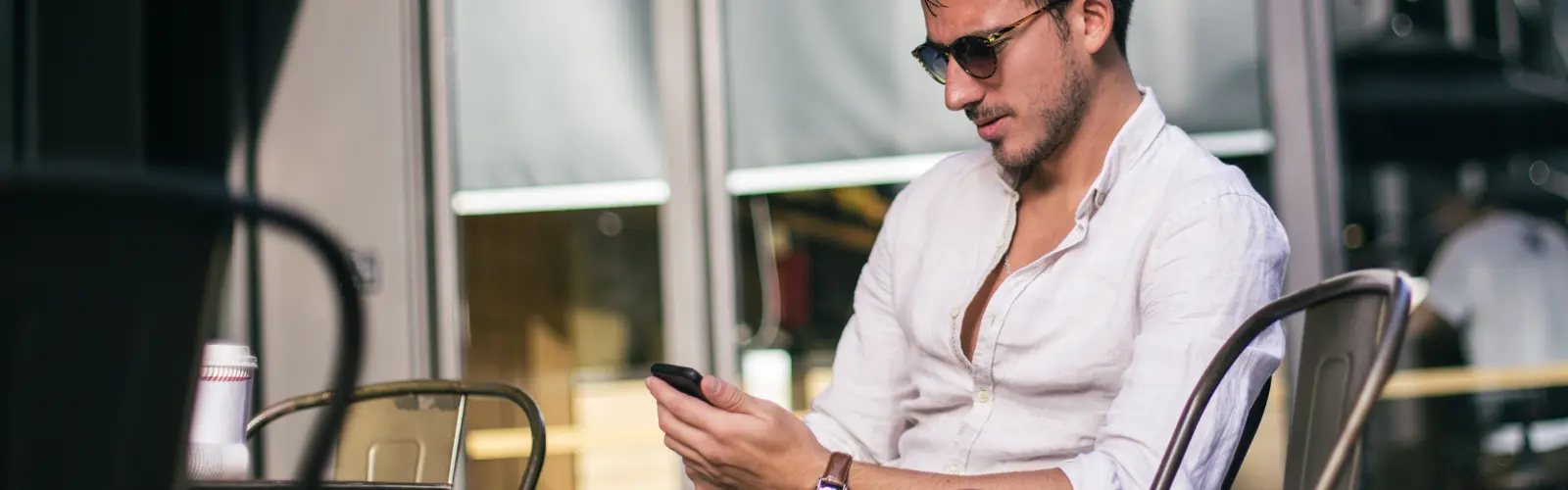 Mann mit Sonnenbrille schaut auf sein Smartphone beim seinem Date