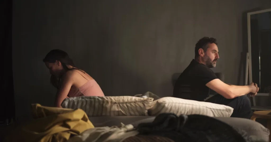 Ein unglückliches Paar sitzt distanziert auf dem Sofa und vermeidet Blickkontakt als Zeichen für Beziehungsprobleme.