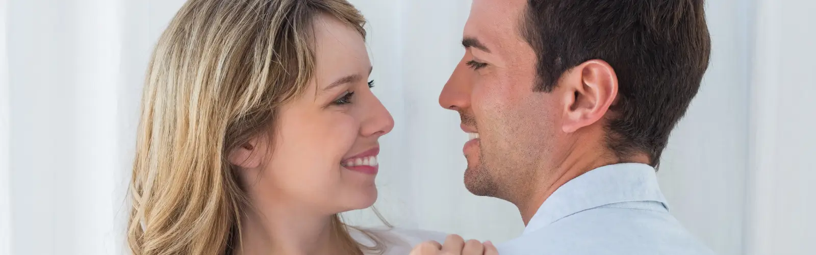 Ein glückliches Paar blickt sich tief in die Augen und lächelt – ein Zeichen für eine gerettete Beziehung.