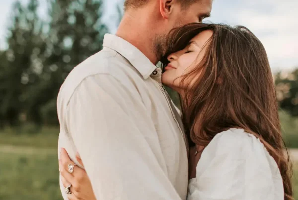 Mann und Frau in inniger Umarmung auf einer Wiese, die Geborgenheit und tiefe Verbindung darstellt.