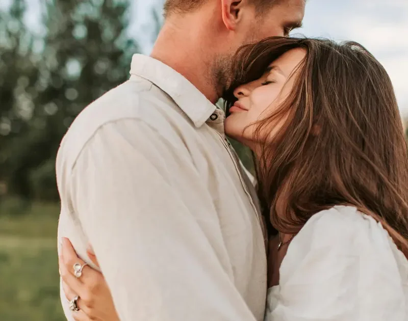 Mann und Frau in inniger Umarmung auf einer Wiese, die Geborgenheit und tiefe Verbindung darstellt.