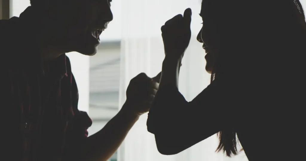 Silhouette eines Paares im Profil, das sich im Schatten heftig streitet – Symbol für Warnsignale einer kaputten Beziehung.