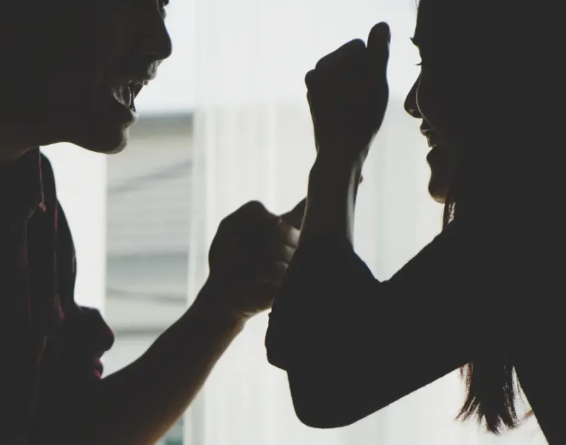 Silhouette eines Paares im Profil, das sich im Schatten heftig streitet – Symbol für Warnsignale einer kaputten Beziehung.