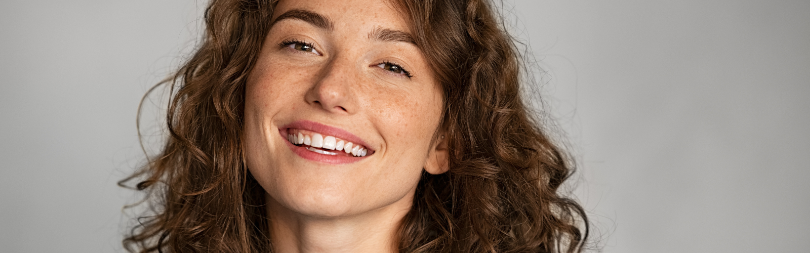 Selbstbewusste Frau lächelt in die Kamera und steht für die weibliche Perspektive beim Dating