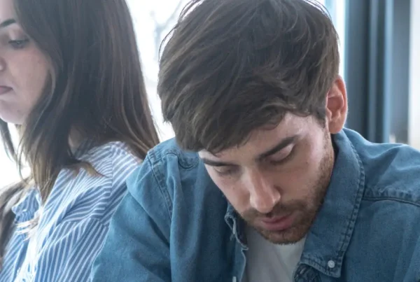 Paar sitzt emotional distanziert nebeneinander, ein Mann wirkt zurückgezogen – typisches Anzeichen von Bindungsangst