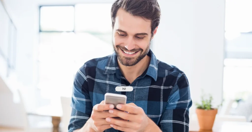 Mann lächelt beim Schreiben einer anonymen Nachricht in einem kostenlosen Chatroom ohne Anmeldung.