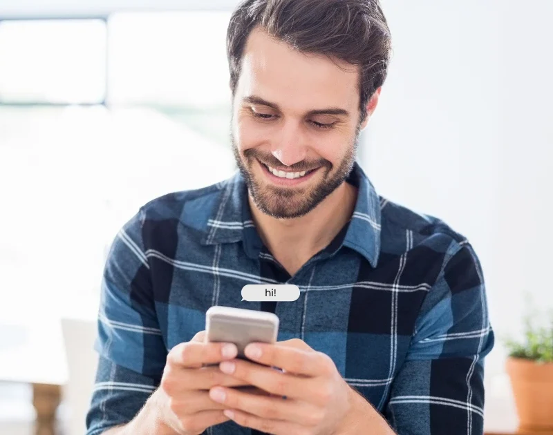 Mann lächelt beim Schreiben einer anonymen Nachricht in einem kostenlosen Chatroom ohne Anmeldung.