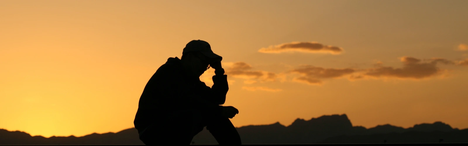 Silhouette eines nachdenklichen Mannes vor einem Sonnenuntergang, der über Disziplin in verschiedenen Lebensbereichen reflektiert.