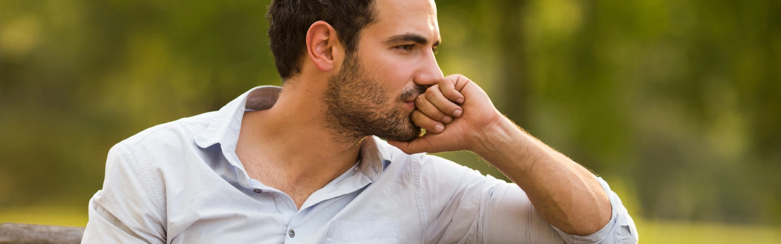 Ein Mann sitzt nachdenklich im Freien und konzentriert sich auf seine Ziele, was Disziplin als Basis für Erfolg darstellt.