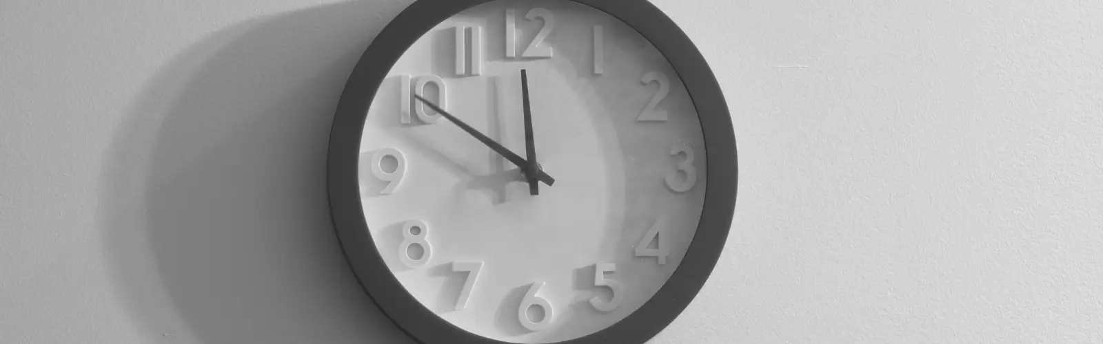 Wanduhr an einer hellen Wand als Symbol für Zeit, Abstand und den Prozess, über den Ex hinwegzukommen.