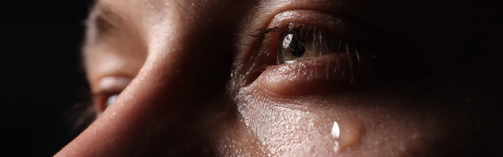 Nahaufnahme eines Auges mit Träne, die emotionalen Schmerz und Trauer nach einer Trennung zeigt.